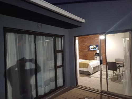 a room with a bedroom with a bed and a sliding glass door at Willow Guest house in Vereeniging