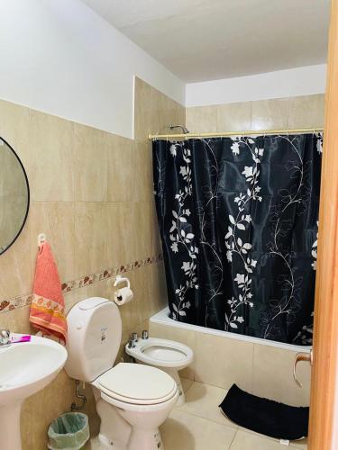 Un baño con inodoro y cortina de ducha. en Alquileres Buendia 3, en Puerto Madryn