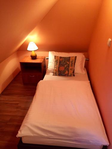a small bedroom with a white bed with a lamp at Penzion U Golema Blansko in Blansko