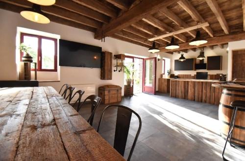une grande table en bois et des chaises dans une pièce dans l'établissement LE RELAIS DES CALECHES - La Jungle Room, à Broué