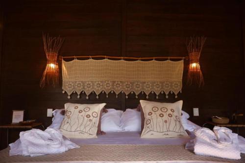 a large bed with white pillows and a canopy at Alma Charme Atins in Atins