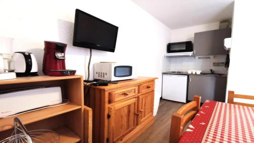 une petite cuisine avec une télévision sur un meuble en bois dans l'établissement Résidence Les Ecrins - ECRINS211 - APPARTEMENT 4 PERSONNES, SECTEUR 1700M AVEC BALCON MAE-7341, à Les Prés