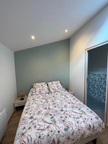 a bedroom with a bed with a floral bedspread at Les Hirondelles B in Le Crotoy