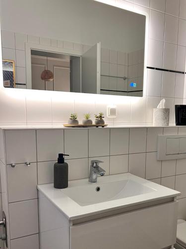 a white bathroom with a sink and a mirror at ZUHAUSE AM MEER mit Sonnenbalkon in Strand- und Altstadtnähe in Warnemünde