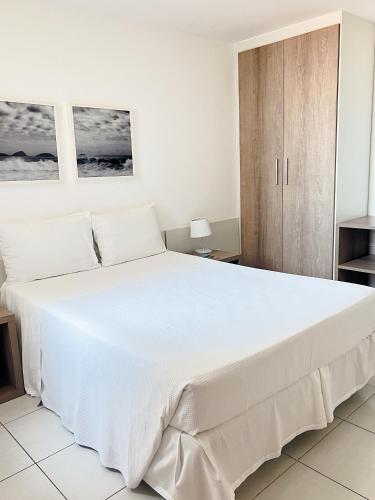 a large white bed in a bedroom with a cabinet at Promenade Prime Itaboraí in Itaboraí