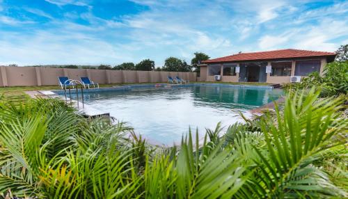 a swimming pool with blue chairs in a yard at THE PREMIER GIR RESORT in Sasan Gir