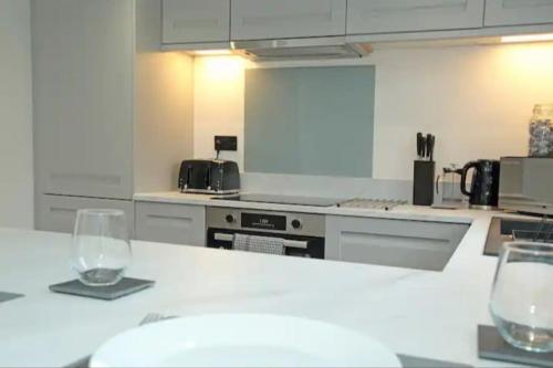 a kitchen with two wine glasses on a counter at Modern Luxury 4 Bed House in Heart of Macclesfield in Macclesfield