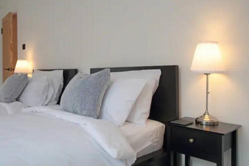 a bed with white pillows and a table with a lamp at Modern Luxury 4 Bed House in Heart of Macclesfield in Macclesfield