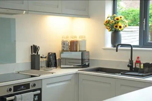 a white kitchen with a sink and a microwave at Modern Luxury 4 Bed House in Heart of Macclesfield in Macclesfield