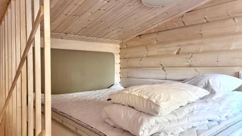a bunk bed with white pillows and a wooden wall at Villa Meriheinä Yyteri in Pori