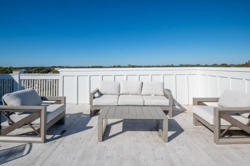 a patio with two chairs and a couch and a table at Luxury New Build with Oceanview - Grow With The Flow in Carolina Beach