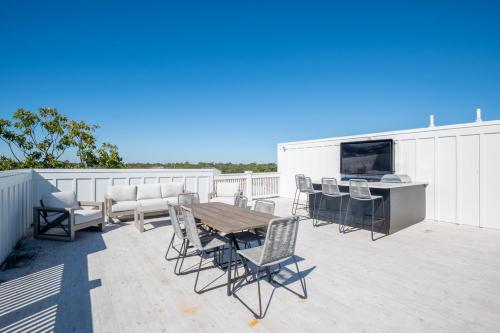 a patio with a table and chairs and a television at Luxury Pet Friendly New Build - Go with the Flo 2 in Carolina Beach