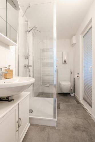 a white bathroom with a sink and a toilet at Sigrids Hüs in Hörnum