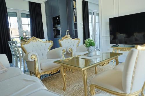 a living room with white chairs and a table and a tv at Vila Safra in Vrnjačka Banja