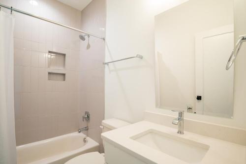 a white bathroom with a sink and a toilet at Luxury New Build with Oceanview - Go with the Flo 1 in Carolina Beach