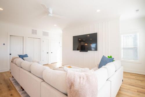 a white living room with a large white couch at Luxury New Build with Oceanview - Grow With The Flow in Carolina Beach