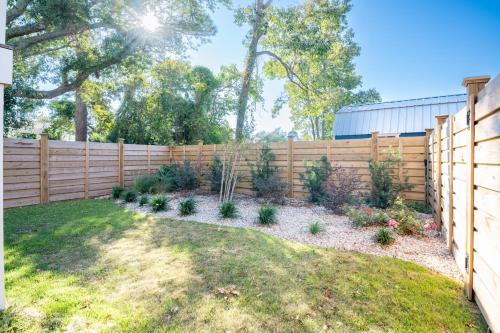 a fence in a backyard with plants at Luxury New Build with Oceanview - Go with the Flo 1 in Carolina Beach
