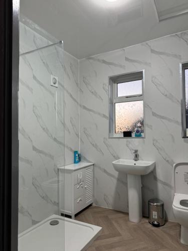 a white bathroom with a sink and a mirror at Nice house with free Parking in Newcastle upon Tyne