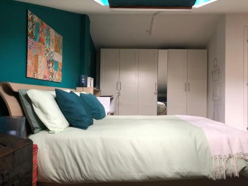 a bedroom with a large white bed with blue pillows at Appartamento Alcoba in Pontedera