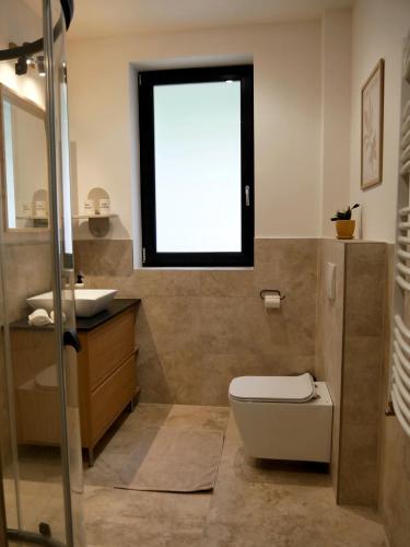a bathroom with a toilet and a sink and a window at Három Hegy Apartman Lillafüred in Lillafüred