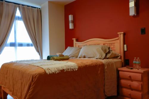 a bedroom with a bed with red walls and a window at La Estancia del Rey David in San Luis Potosí