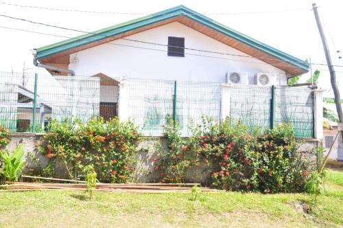 a house with a fence and some bushes at Résidence Merveilles P14 in Kribi