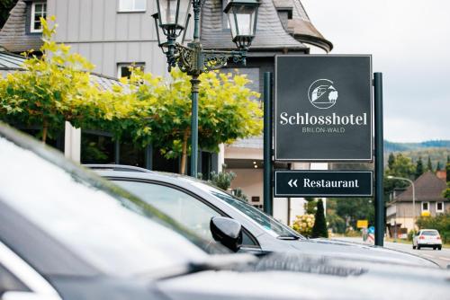 a parking lot with cars parked in front of a sign at Schlosshotel Brilon-Wald in Brilon-Wald