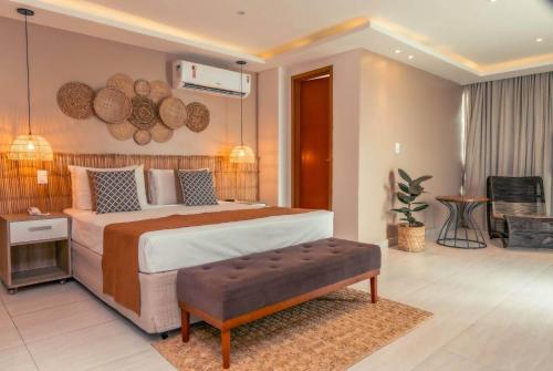 a bedroom with a large bed with a bench in it at Paradiso Peró Praia Hotel in Cabo Frio