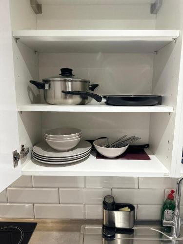 a kitchen shelf with dishes and pots and pans at Timex Studio in Croydon