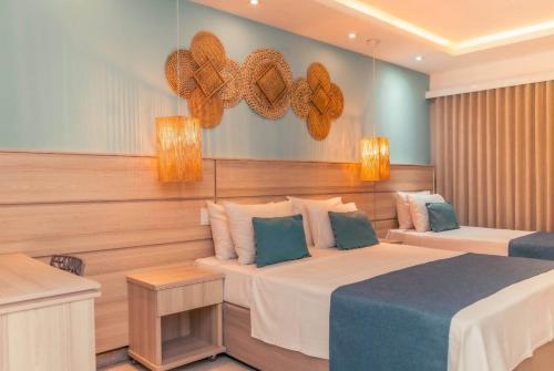 a bedroom with two beds and two lights on the wall at Paradiso Peró Praia Hotel in Cabo Frio
