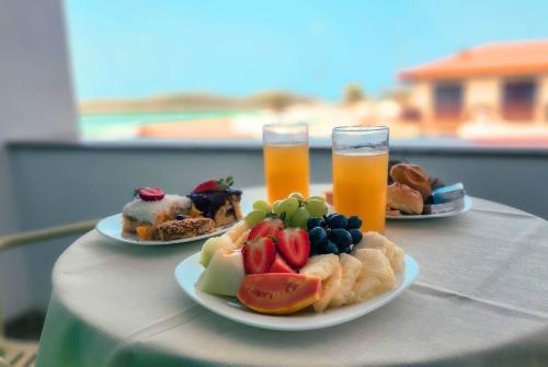 two plates of food and two glasses of orange juice at Paradiso Peró Praia Hotel in Cabo Frio