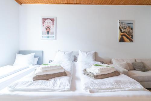 a white bed with pillows on it with a couch at COY Apartments Leoben - Stay Comfortable & Work Smart in Leoben