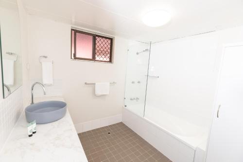 a bathroom with a shower and a blue tub at Currimundi Hotel in Caloundra