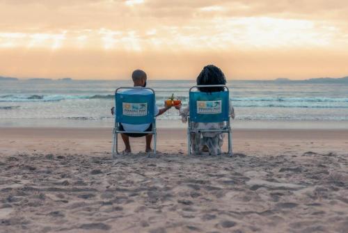 a man and a woman sitting in chairs on the beach at Paradiso Peró Praia Hotel in Cabo Frio