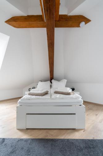 a white bed in a room with wooden ceilings at COY Apartments Leoben - Stay Comfortable & Work Smart in Leoben