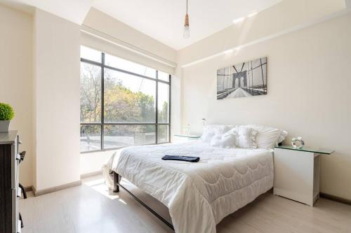 a white bedroom with a bed and a large window at Mexico City MondoMexico Deluxe 2 Bedroom apartments in Mexico City
