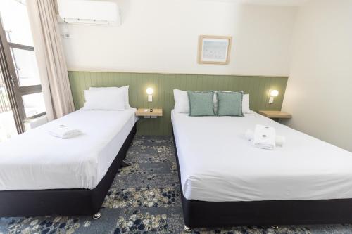 two beds in a small room with two lamps at Currimundi Hotel in Caloundra