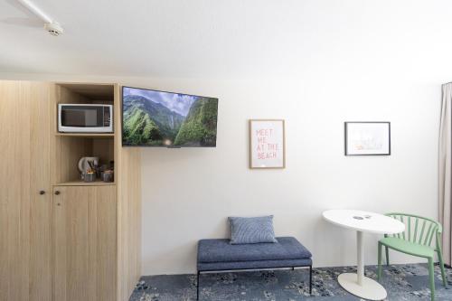 a room with a tv and a chair and a table at Currimundi Hotel in Caloundra