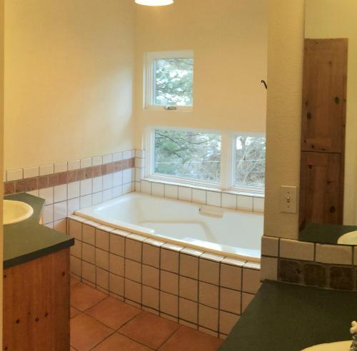 Un baño con bañera, lavabo y ventana. en Creekside Craftsman Cabin with Jacuzzi - Alpine Splendor 6 Mins to downtown, en Boulder