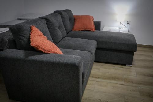 a gray couch with orange pillows in a living room at Sosnówka Pokoje Gościnne in Borne Sulinowo