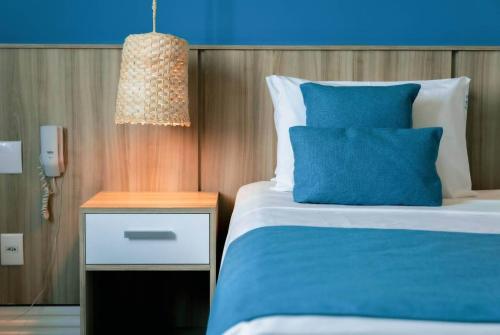 a bedroom with a blue and white bed and a night stand at Paradiso Corporate in Cabo Frio