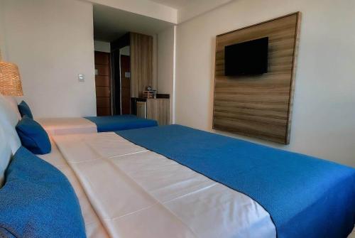 a bedroom with a large bed with a tv on the wall at Paradiso Corporate in Cabo Frio