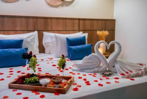 a bed with two swans and a tray of fruit at Paradiso Corporate in Cabo Frio