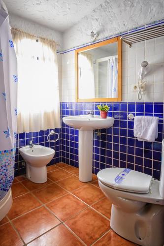 a blue tiled bathroom with a sink and a toilet at Cuevas Pedro Antonio de Alarcon in Guadix