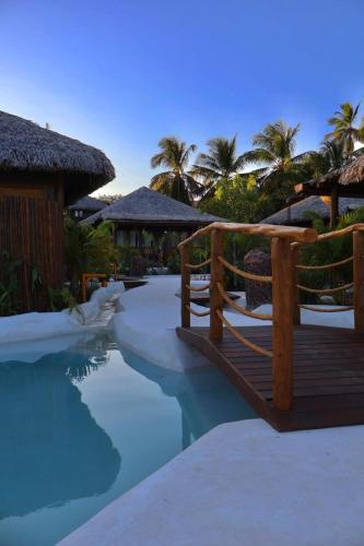 a resort swimming pool with a bridge and a resort at Alma Charme Atins in Atins
