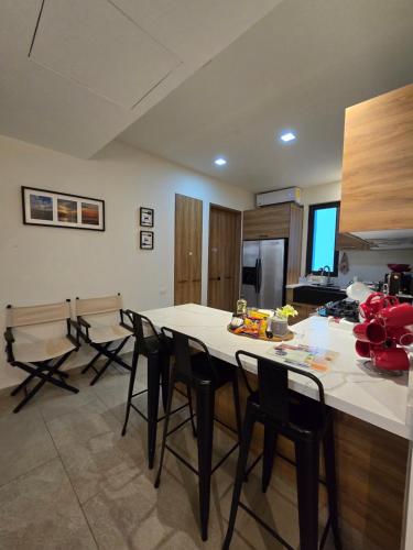 a kitchen with a large white counter and black chairs at LA ISLA RESIDENCES, DEPA DE LUJO, Acapulco Diamante in Acapulco