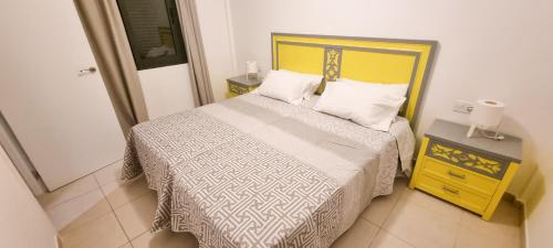 a bedroom with a bed with a yellow and white bedspread at Drago 1 Atlantic Garden apartment in Corralejo