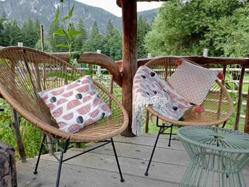 two wicker chairs with pillows sitting on a porch at Alpi Giulie Chalets in Valbruna