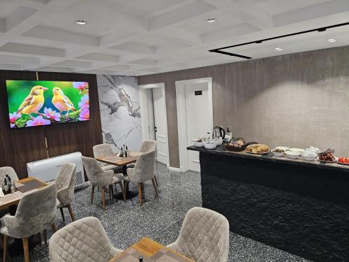 uma sala de espera com mesas e cadeiras e uma televisão em Hotel Royal em Shkodër