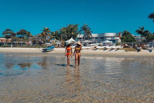 two women standing in the water on a beach at Hotel Paradiso del Sol in Cabo Frio